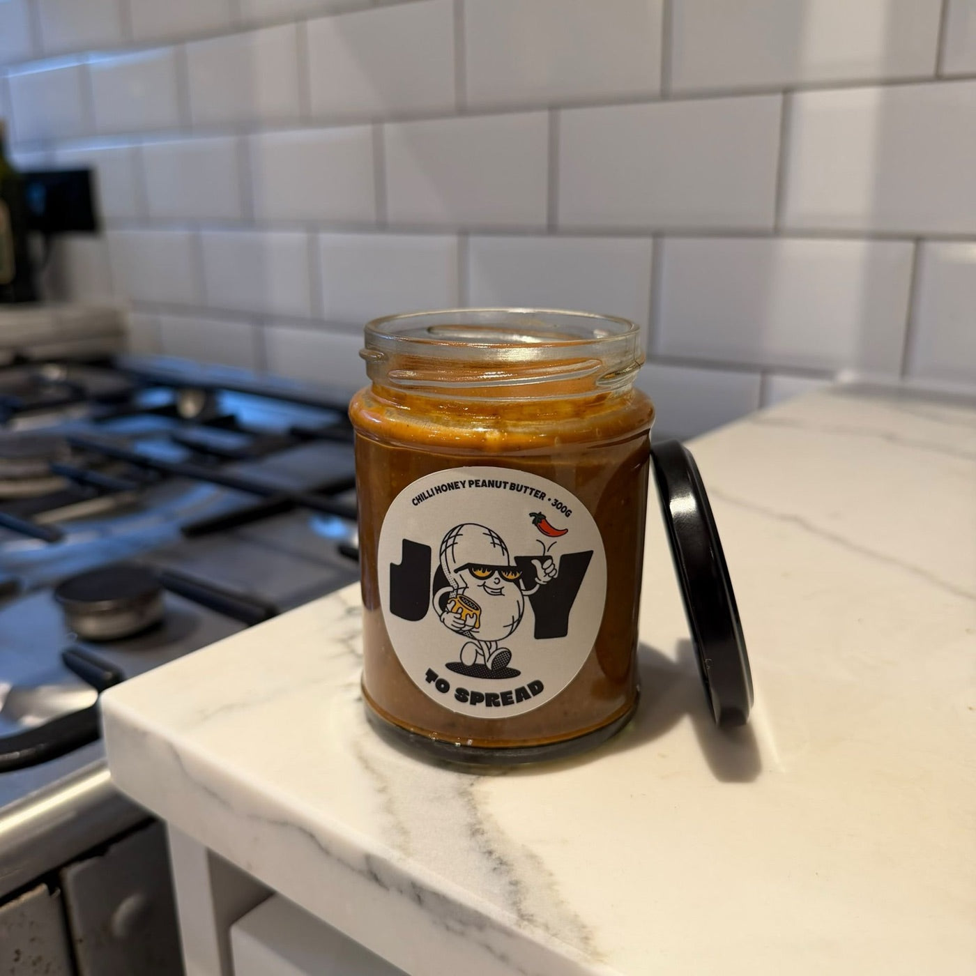 An open jar of Joy to Spread on a kitchen counter, lid resting beside it